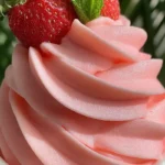 Strawberry Dole Whip served in a pink cup, topped with fresh strawberries and mint leaves.